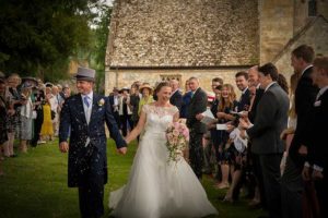 Couple walking under confetti at a Cotswolds wedding